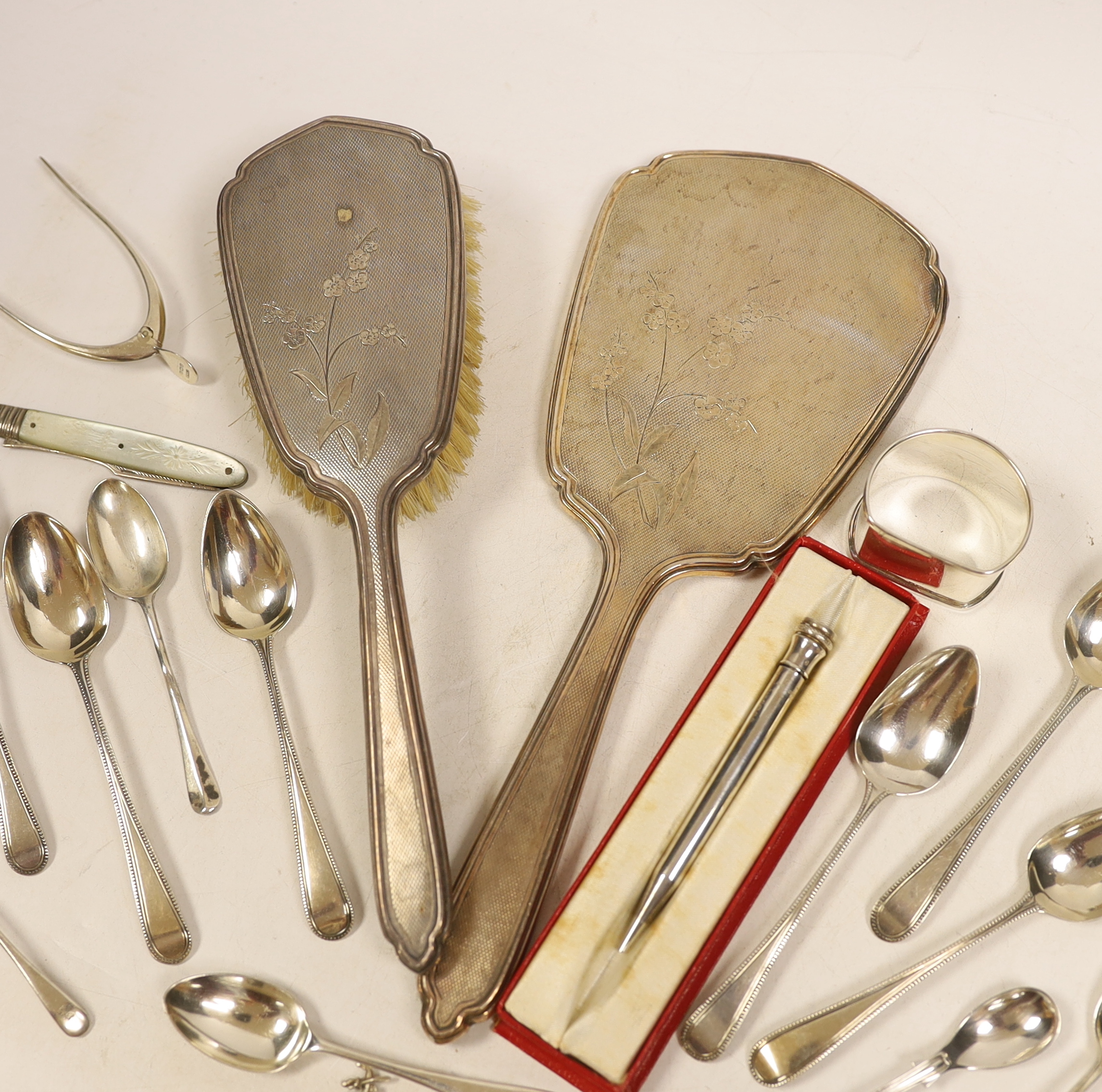 A silver mounted hand mirror and hair brush and sundry small silver including teaspoons, Georgian travelling fork, wishbone sugar nips, napkin rings and pencil.